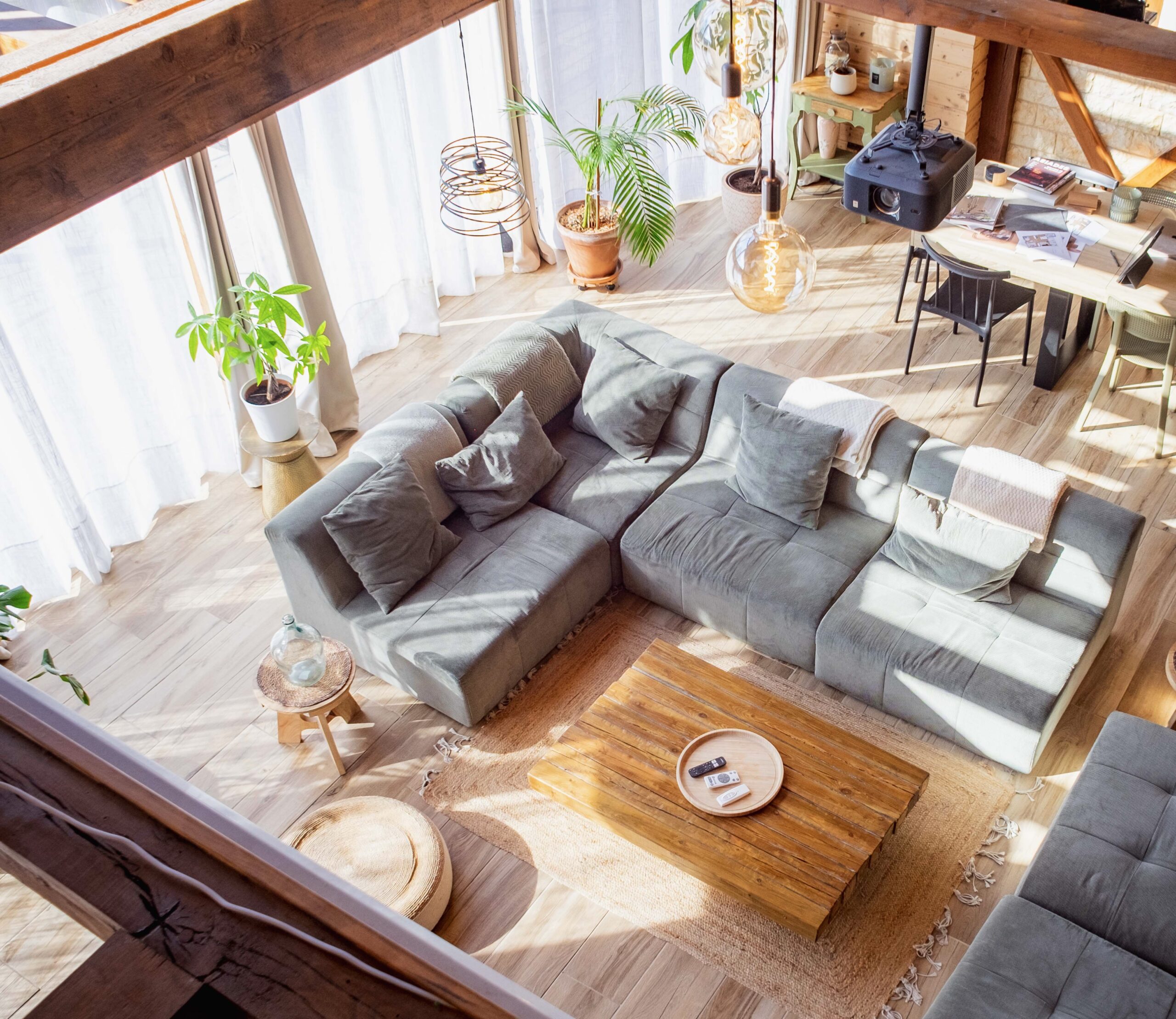 Salon California Farmhouse vu en plongée — canapé en lin, table basse en bois massif, poutres apparentes et lumière naturelle